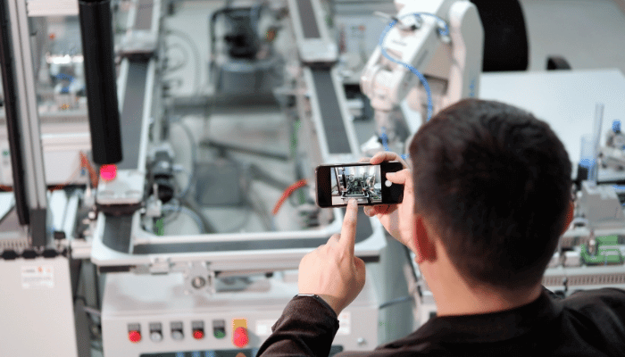 Man using smartphone for augmented reality in an industry 4.0 smart factory. 