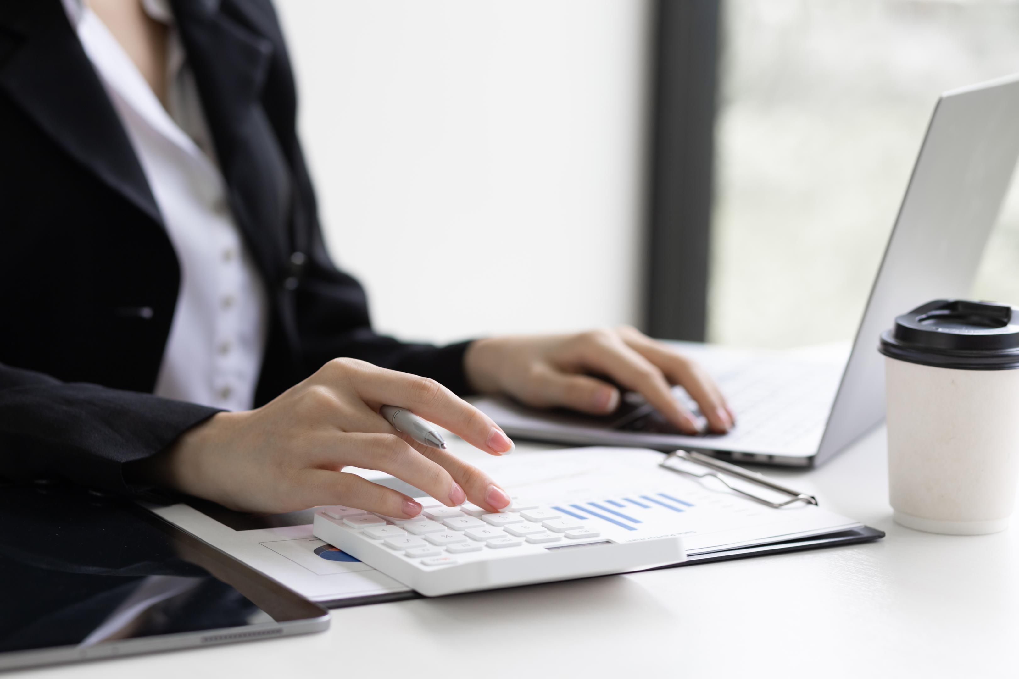 "Businesswoman in office, using a calculator to allocate real estate budgets efficiently."