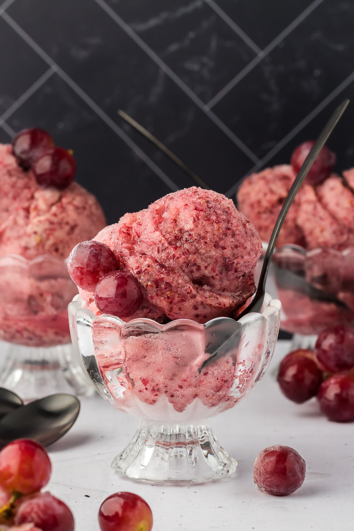 a glass dish of red grape sorbet with a spoon