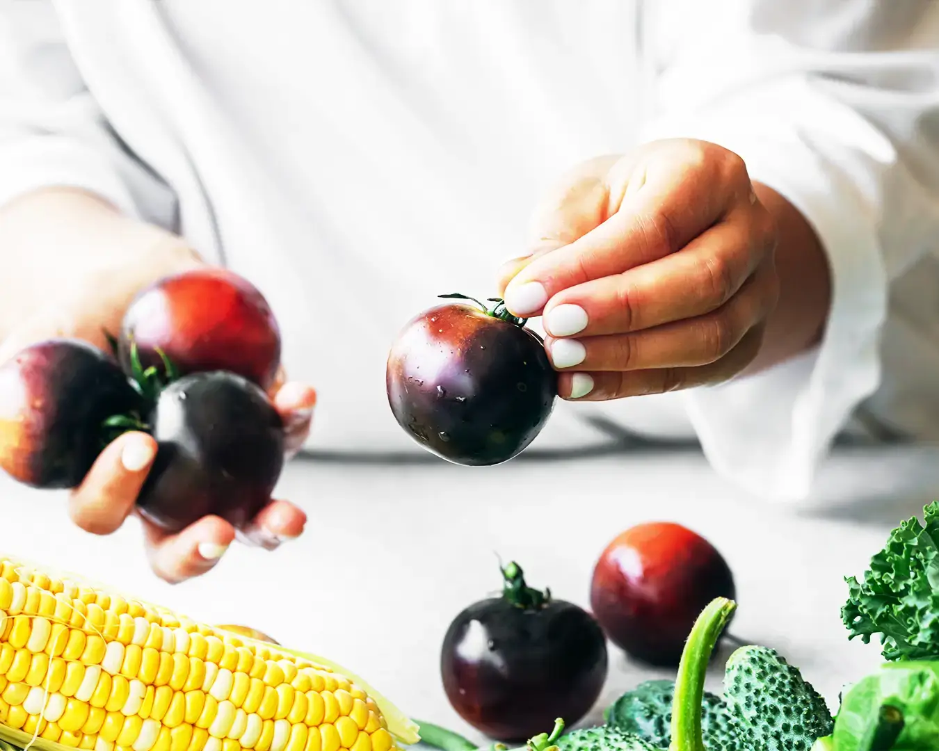 Chef selecting fresh tomatoes and vegetables for restaurant menu preparation