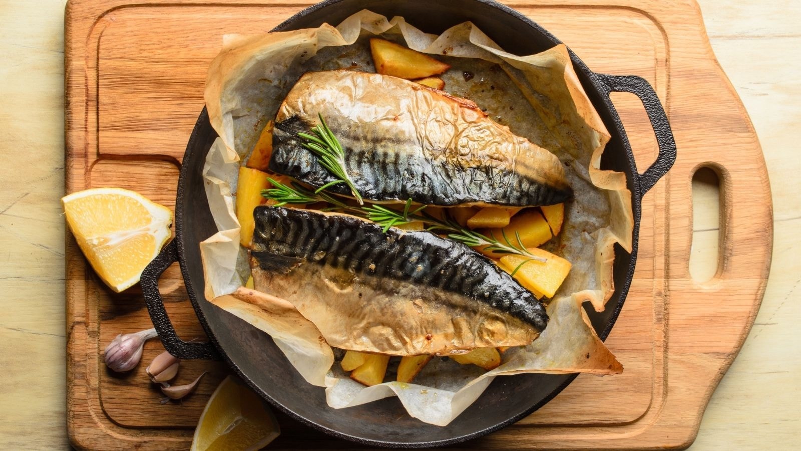 Grilled mackerel fillets with lemon, potatoes, and herbs in cast iron pan