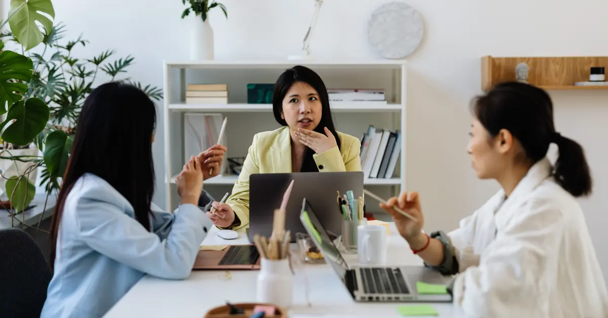 A woman meeting with employees in an office setting, discussing "can a sole proprietor have employees?"