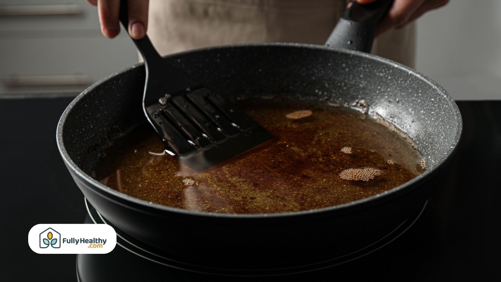 Spatula stirring hot oil in non-stick frying pan on stovetop