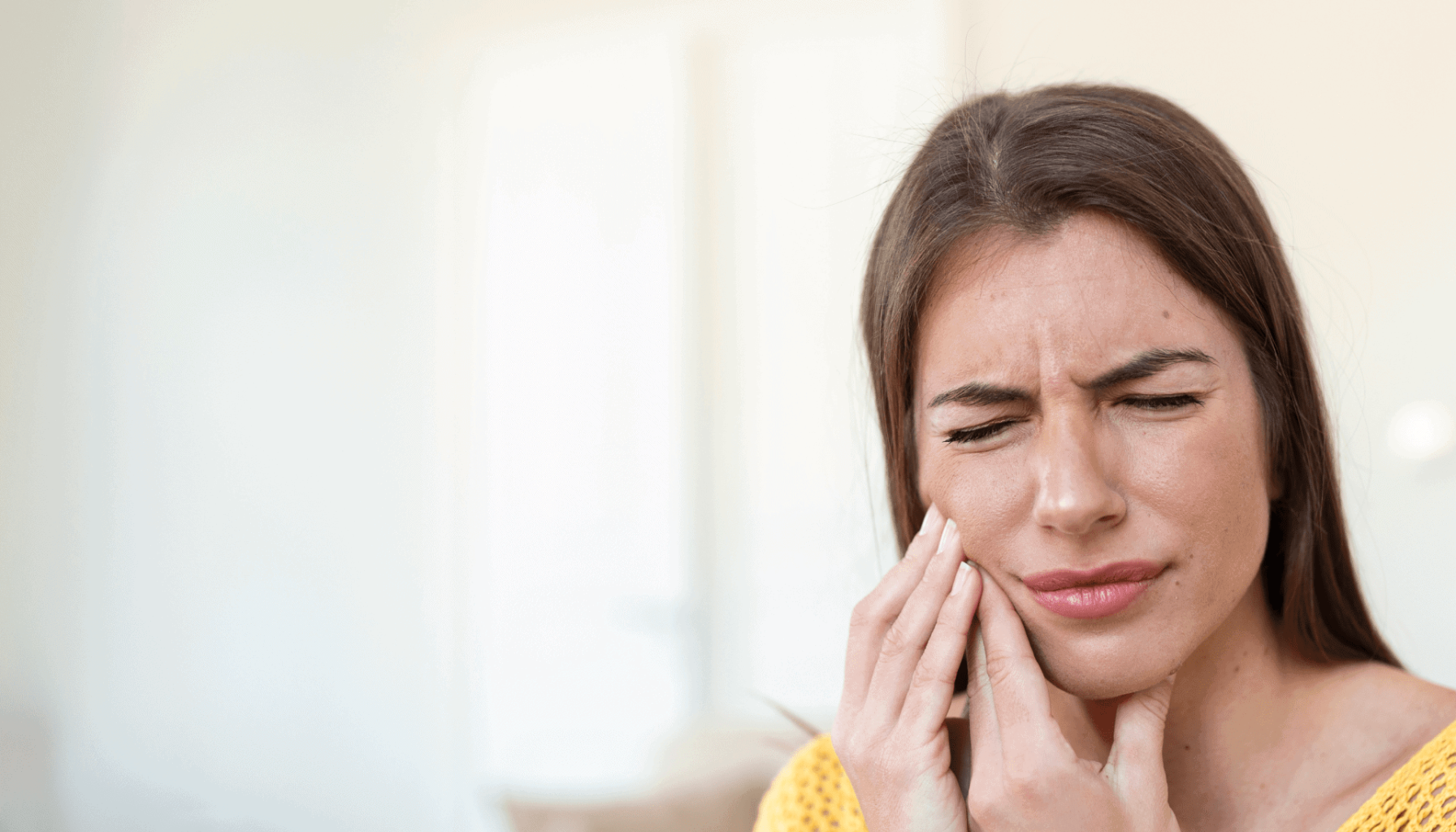 Kvinne med smertefullt uttrykk holder seg til kjeven.