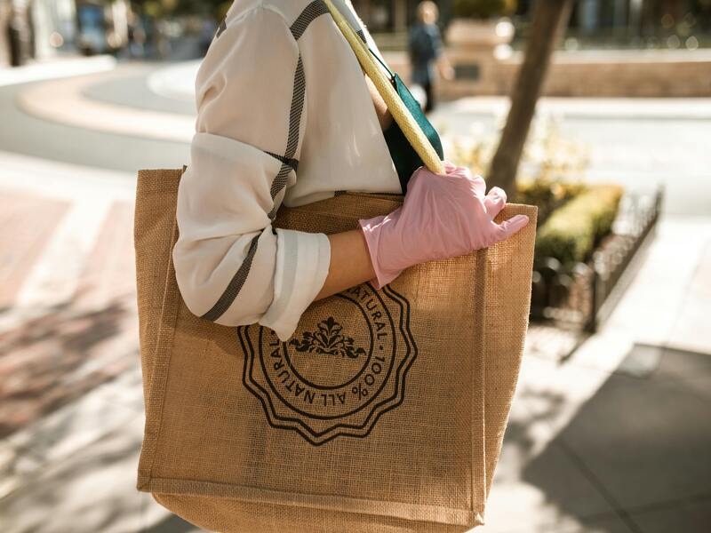 A person carrying a brown jute tote bag. 