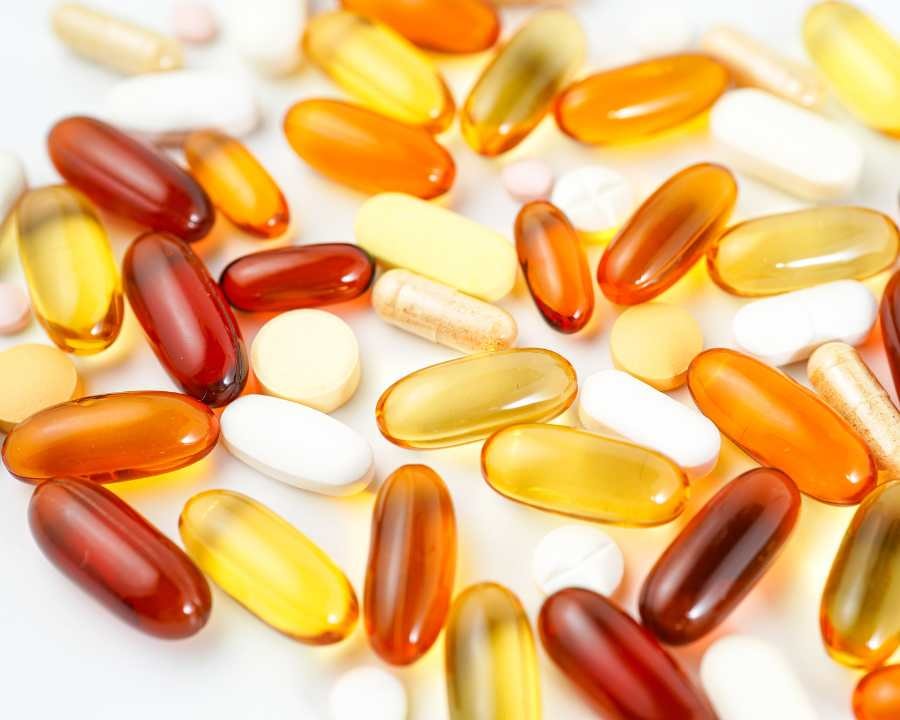 Yellow, orange, and white softgel supplements and tablets on bright white background – Supplements Nutrition by The Good Stuff