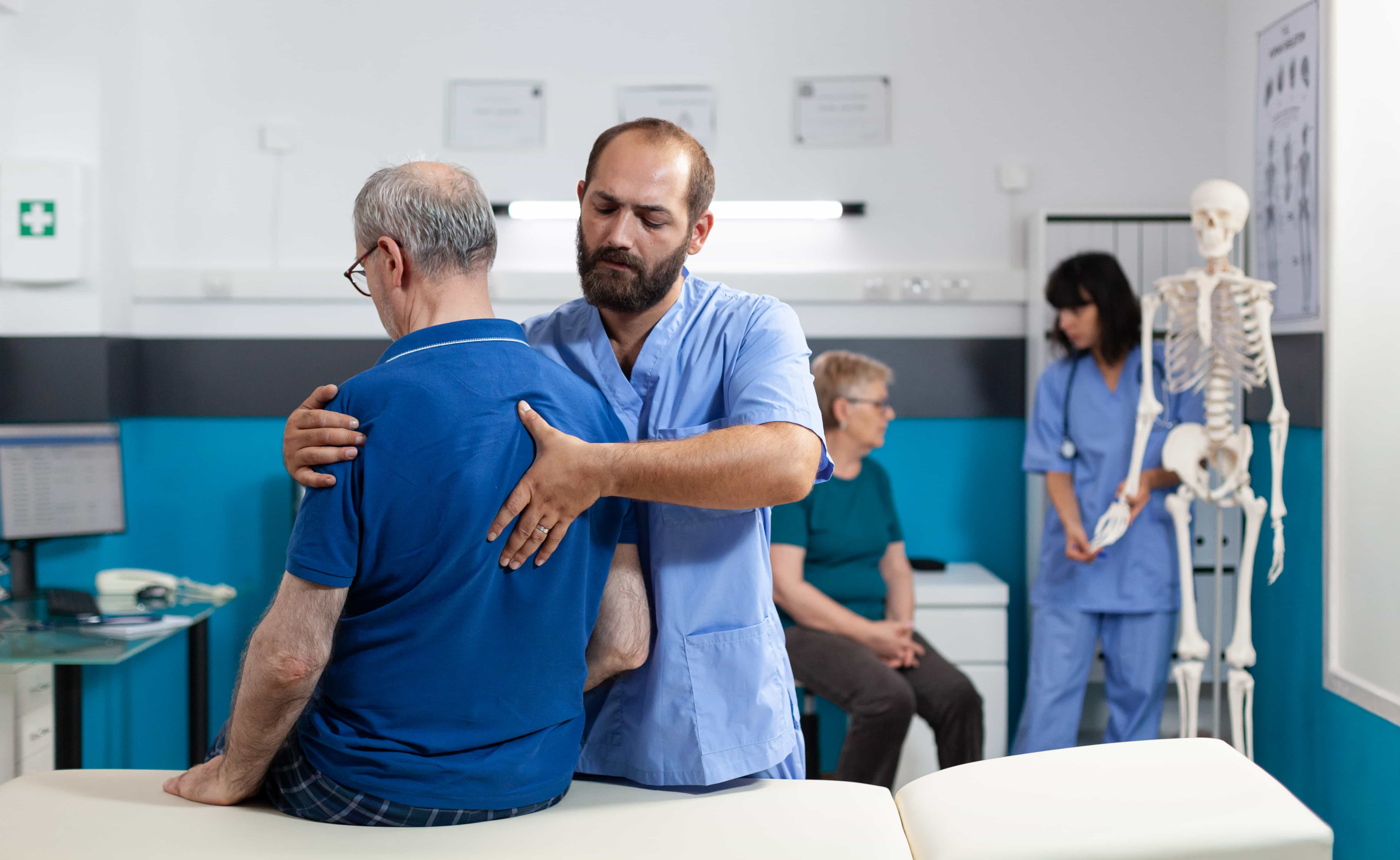 Older man receiving physical therapy at a New South Wales private hospital. Patient is wearing a bright blue polo shirt.  He is sitting on the table.