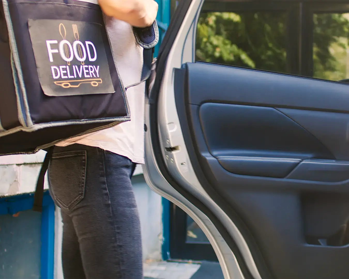 Food delivery driver carrying insulated delivery bag to transport restaurant orders