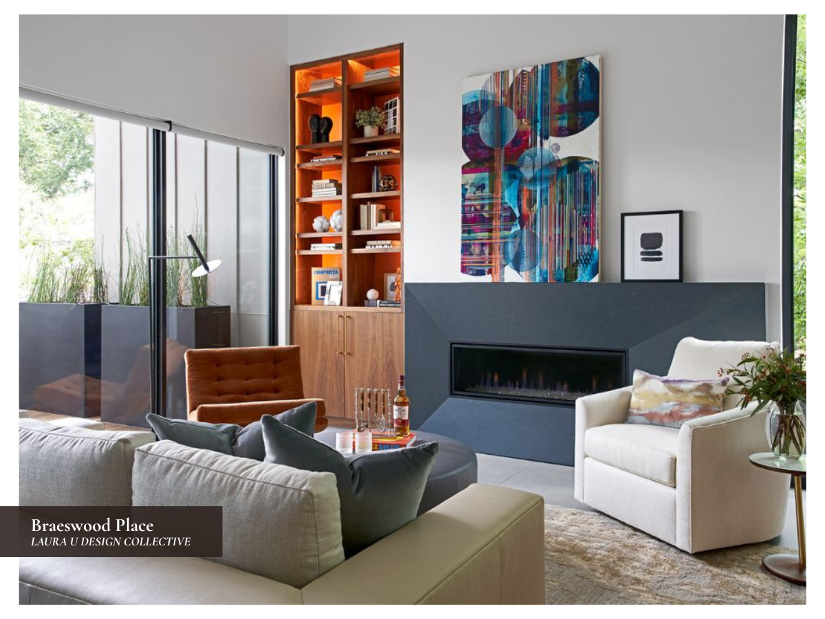Modern library with illuminated walnut shelving, orange lounge chair, blue-gray fireplace surround, and colorful abstract artwork.