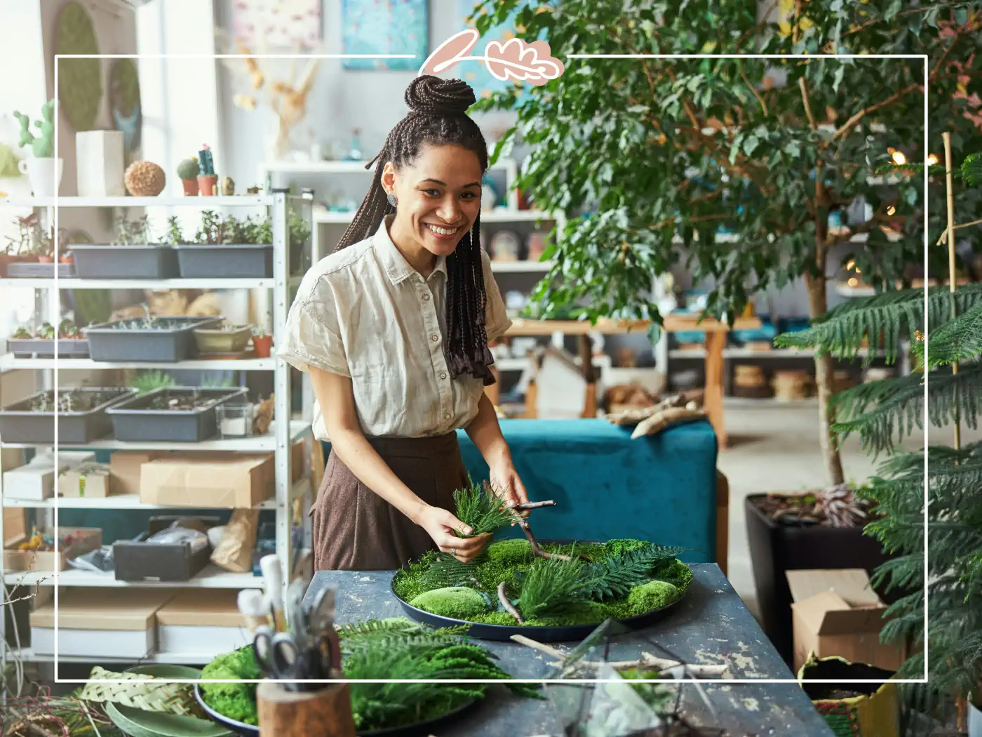 Young florist creating a lush green plant arrangement at a table in a well-stocked flower shop - Fabulous Flowers and Gifts