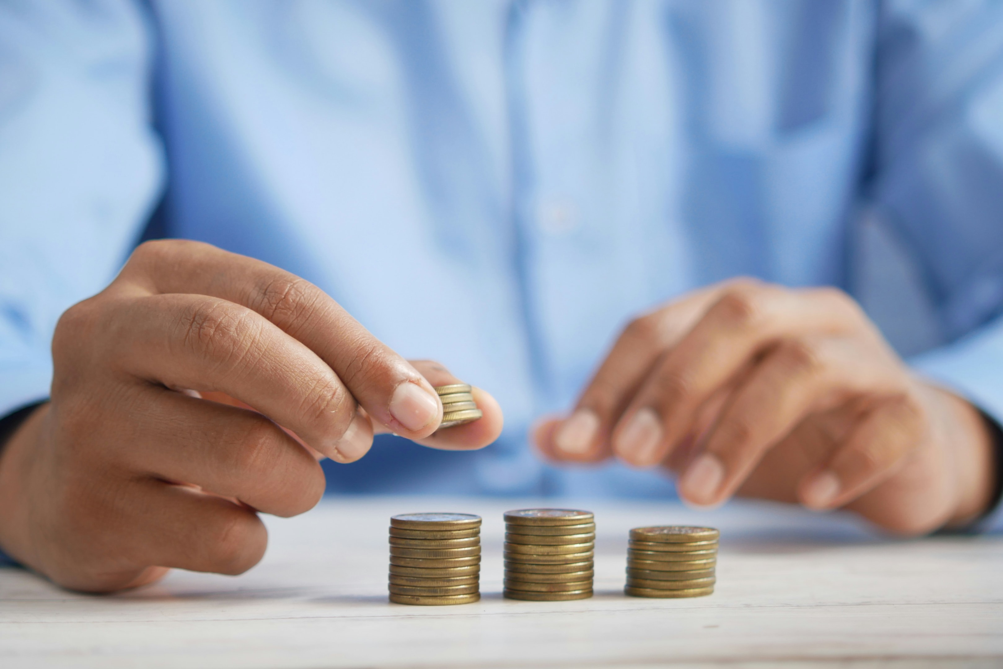 Real estate investor stacks coins on his desk, showing financial literacy over time.