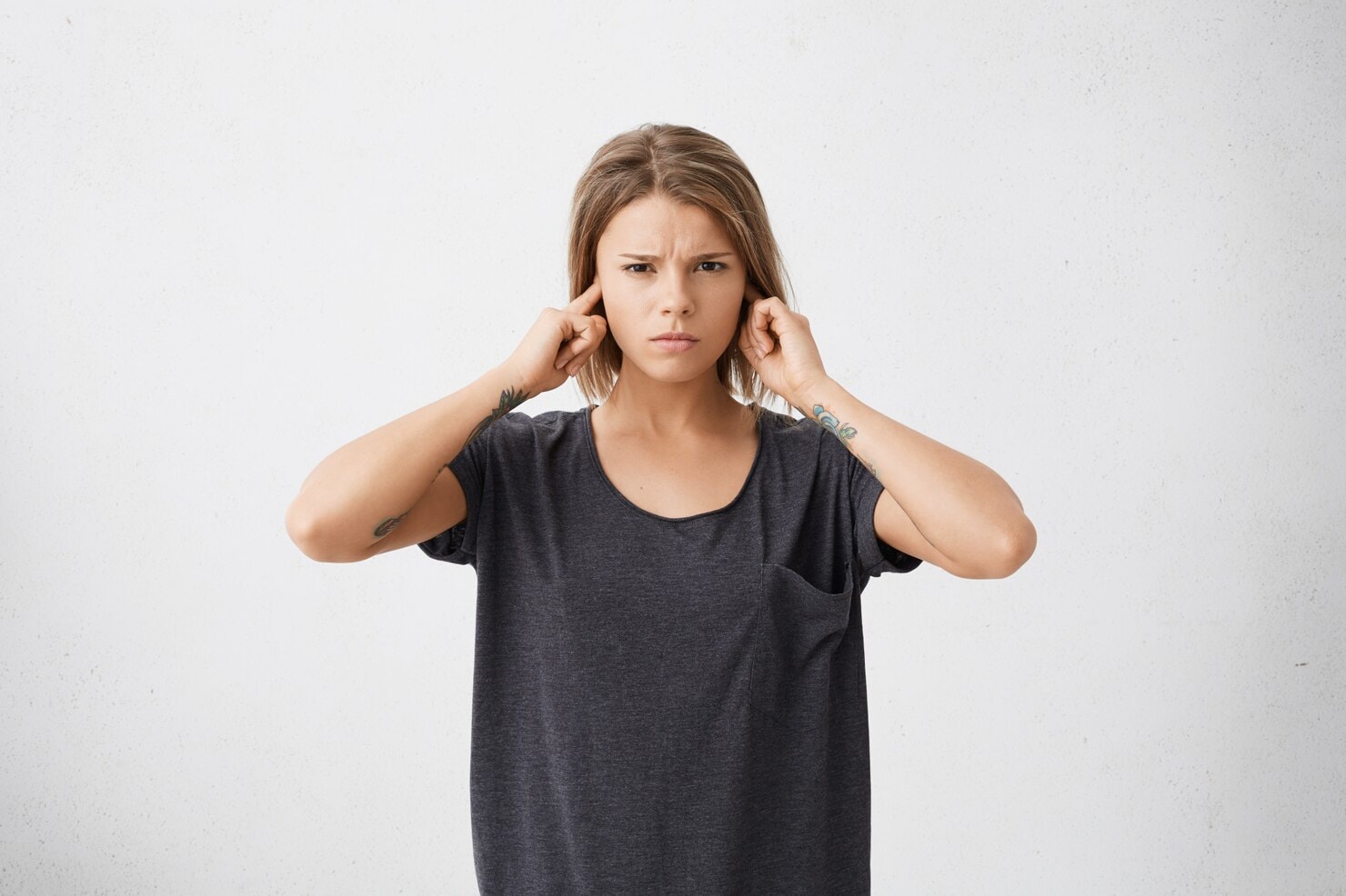 Young female covering her ears to block sounds