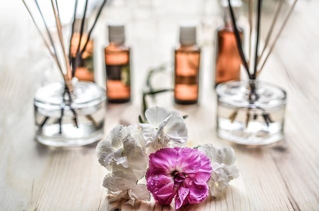 An image of essential oils, incense sticks, and flowers on a table. 