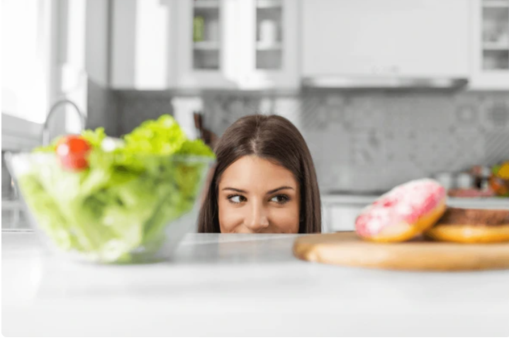 A person looking at a variety of sugary foods, contemplating their sugar cravings.