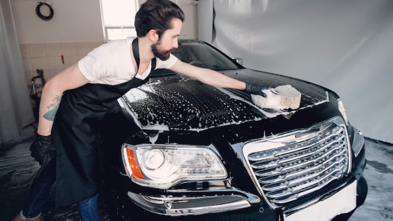 A professional using water and soap to clean PPF coated car