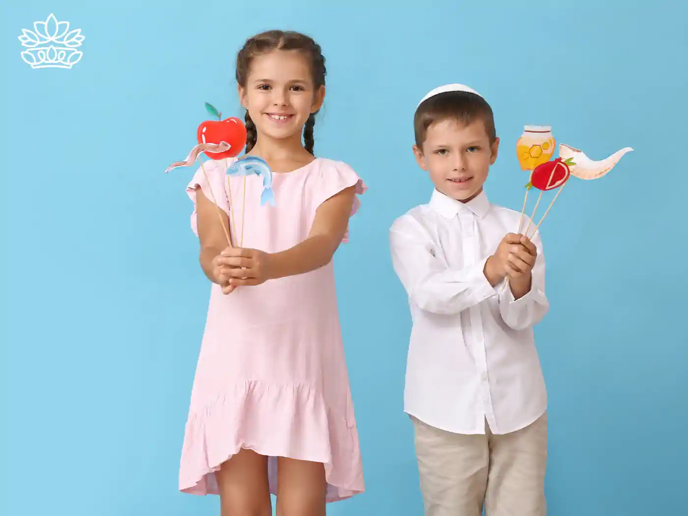 Two children holding Rosh Hashanah themed props against a blue background - Fabulous Flowers and Gifts, Rosh Hashanah Flowers Collection.