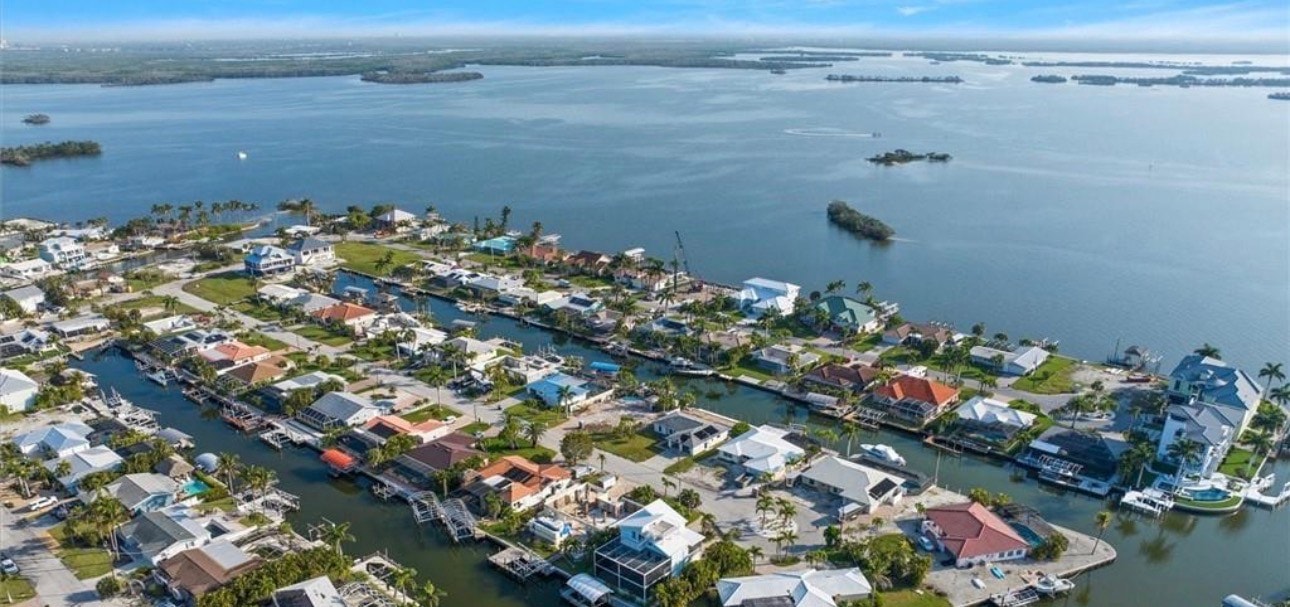 The image depicts a modern luxury kitchen featuring elegant quartz countertops and large windows that offer breathtaking water views, creating an inviting ambiance perfect for family gatherings and morning coffee. This coastal charm is ideal for those seeking a serene lifestyle in Fort Myers Beach, with easy access to pristine beaches and nearby restaurants.