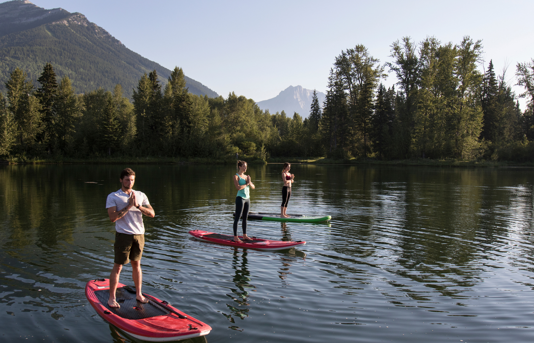 Three people doing yoga on stand up paddle boards on a mountain lake - Adventure Wise Travel Gear