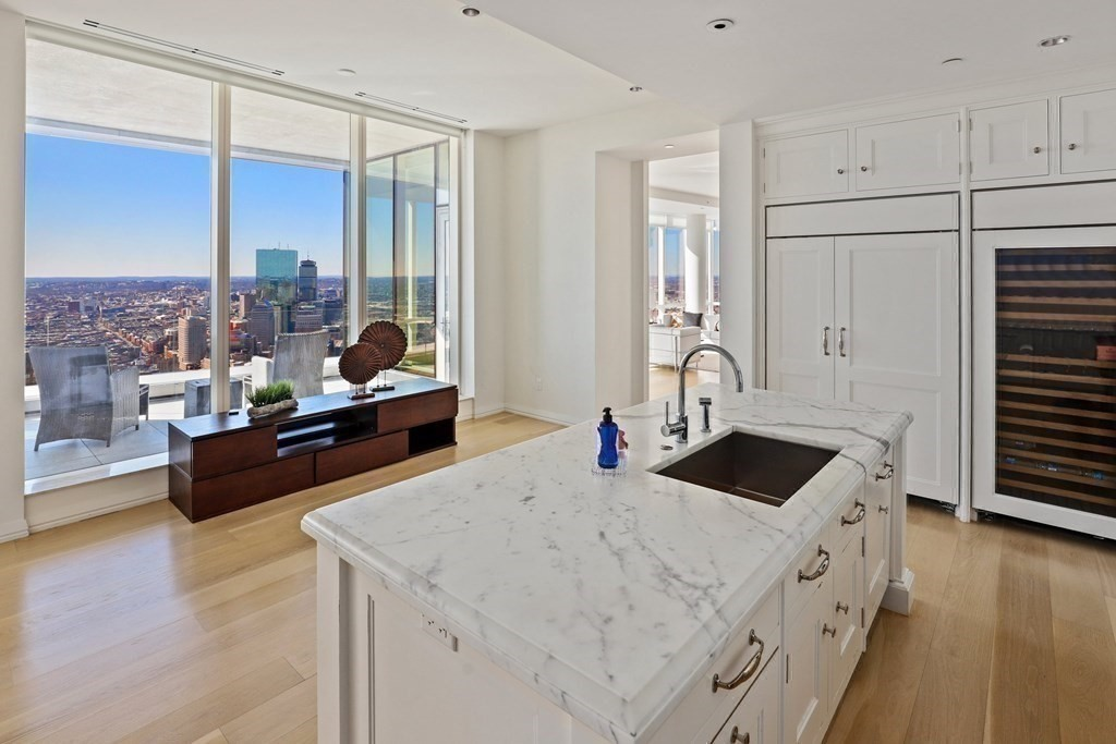 A look a high-rise apartment's kitchen with ceiling to floor windows and a patio