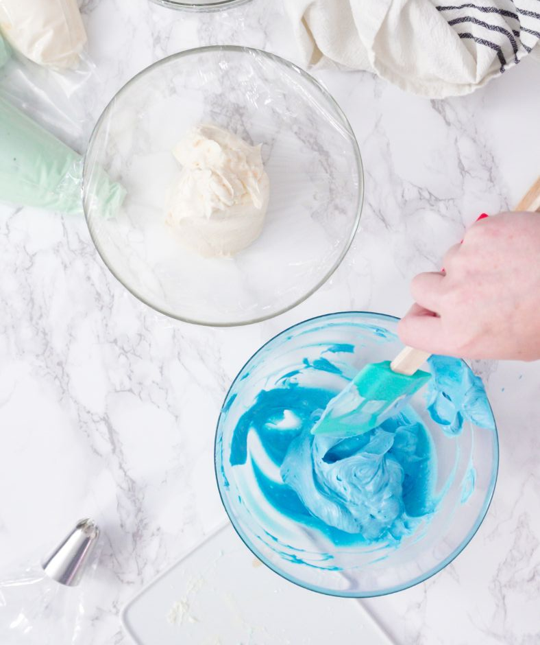 two bowls of frosting - one bowl of white and one blue