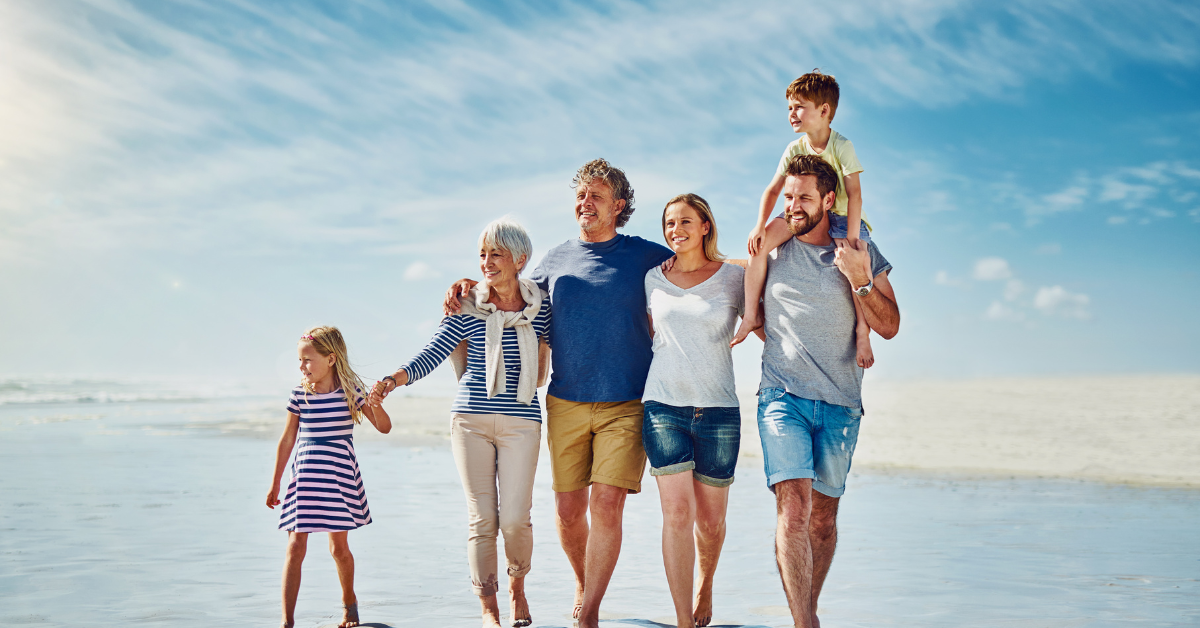 Multi-generational family walking along the beach in Brick, NJ enjoying a sunny Jersey Shore day — ideal destination for family friendly vacation rentals.