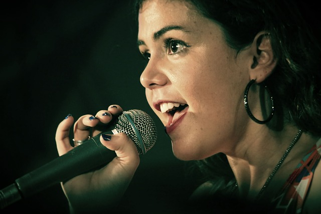 An image of a woman singing into a microphone to warm up her voice for vocal health. 