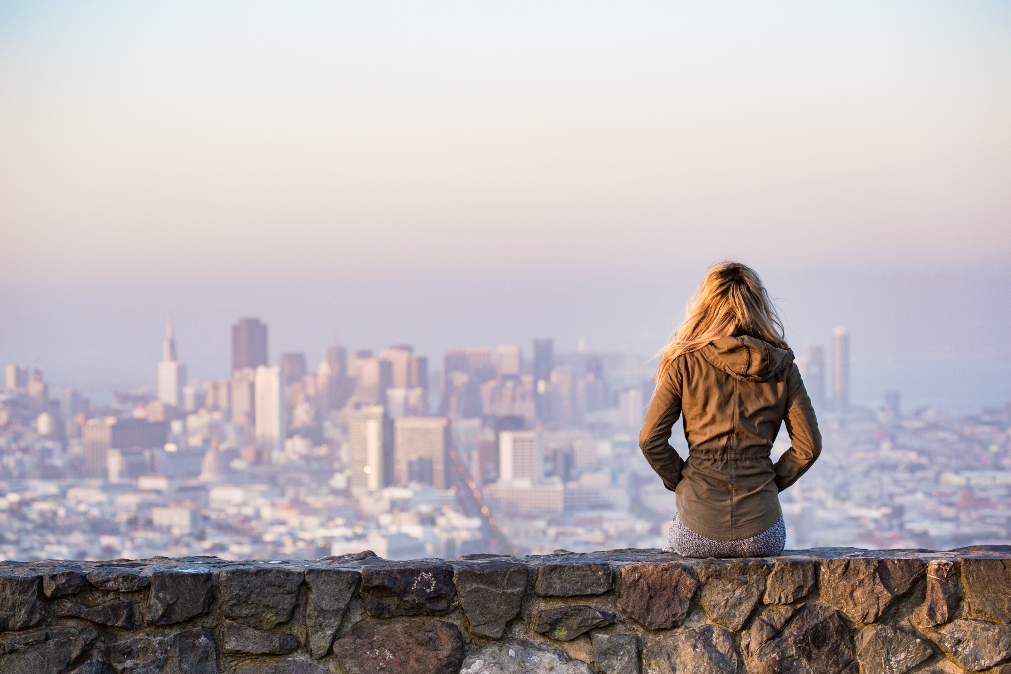 Woman sitting on brick platform admiring a city
