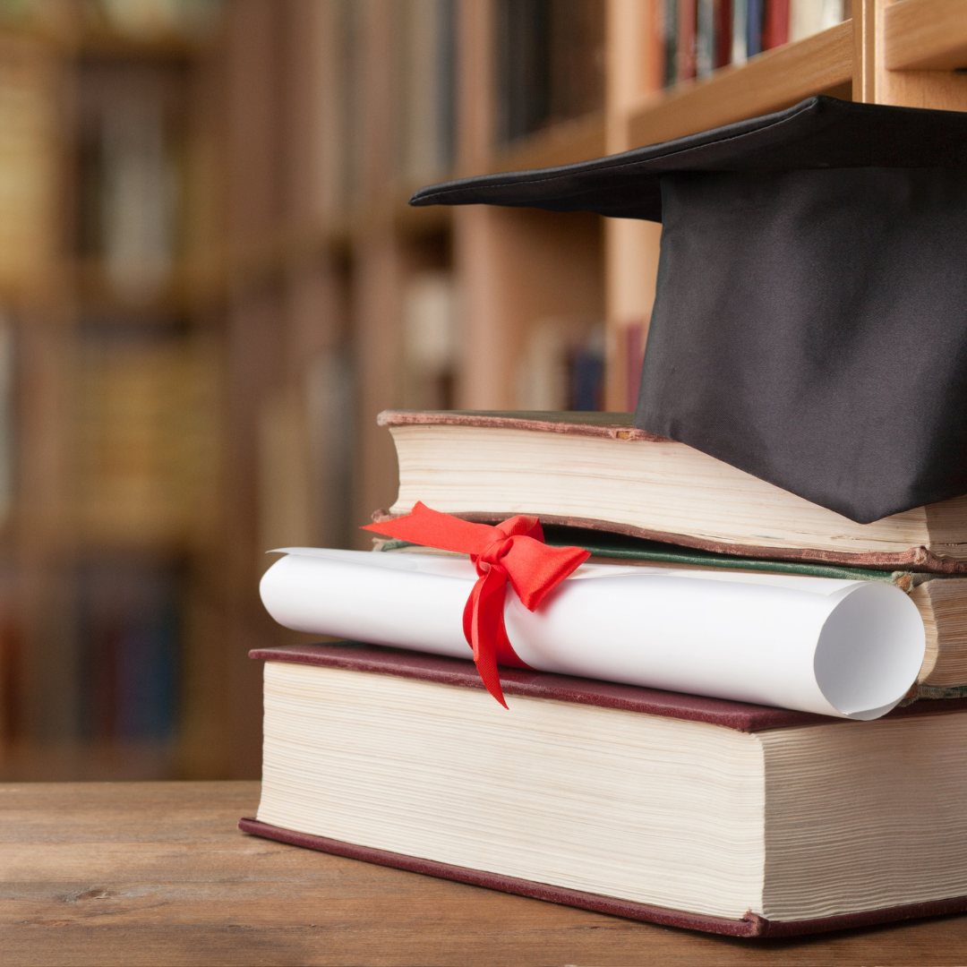 books and mortarboard hat in a library