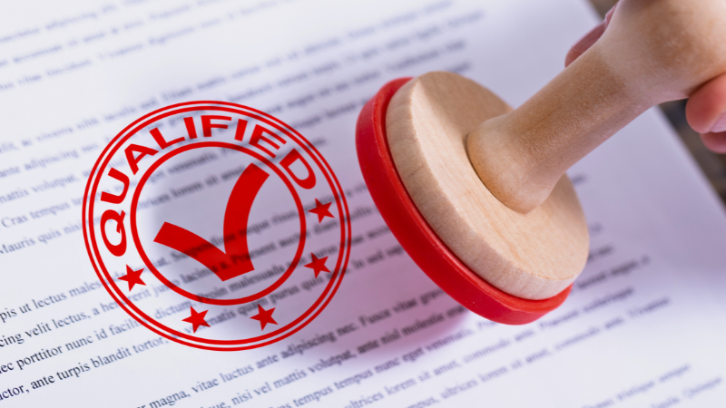 A rubber stamp is placed on a document with the word qualified