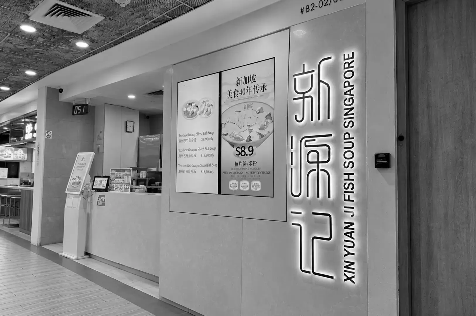 A traditional sliced fish bee hoon stall with menu boards, food preparation counters, kitchen equipment, and cooking ingredients.