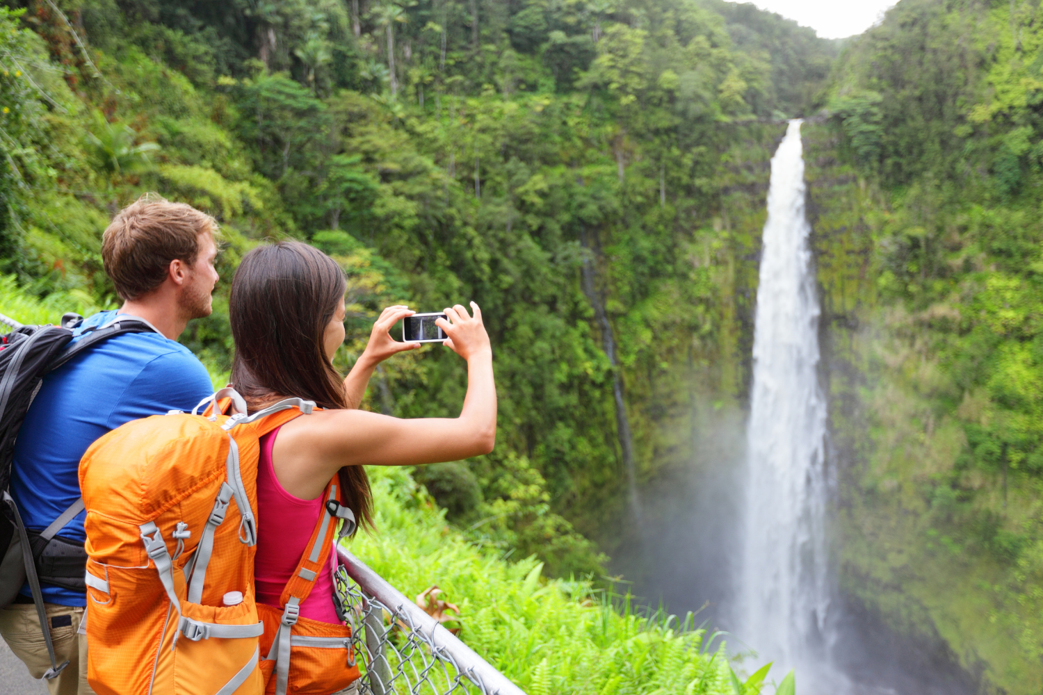 a man and woman taking photos of pu uka oku falls 