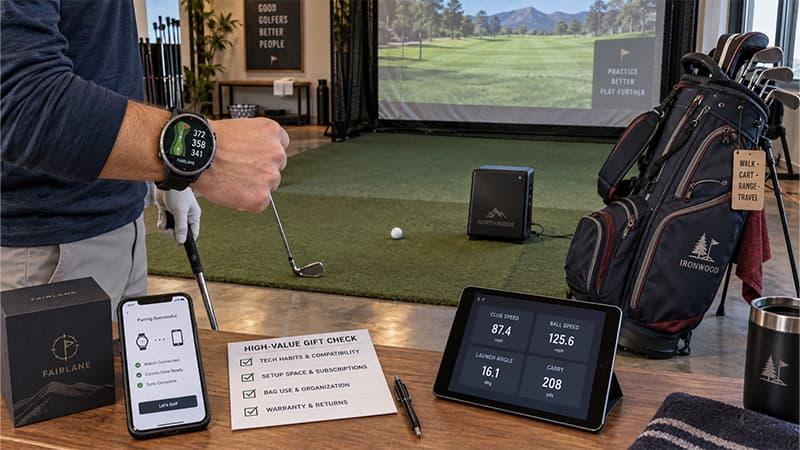 Golfer testing a GPS watch and personal launch monitor beside a premium golf bag in an indoor practice bay
