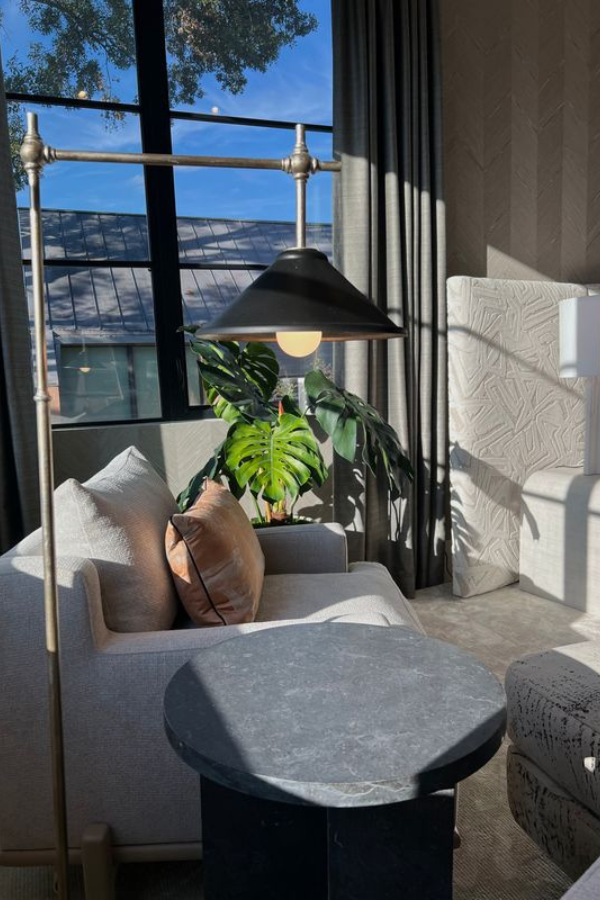 a living room vignette with end table, chair, floor lamp, and headboard
