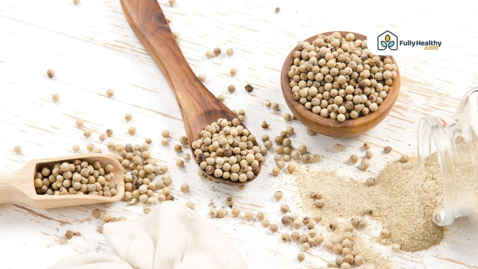 White peppercorns and ground white pepper in wooden spoons and bowls