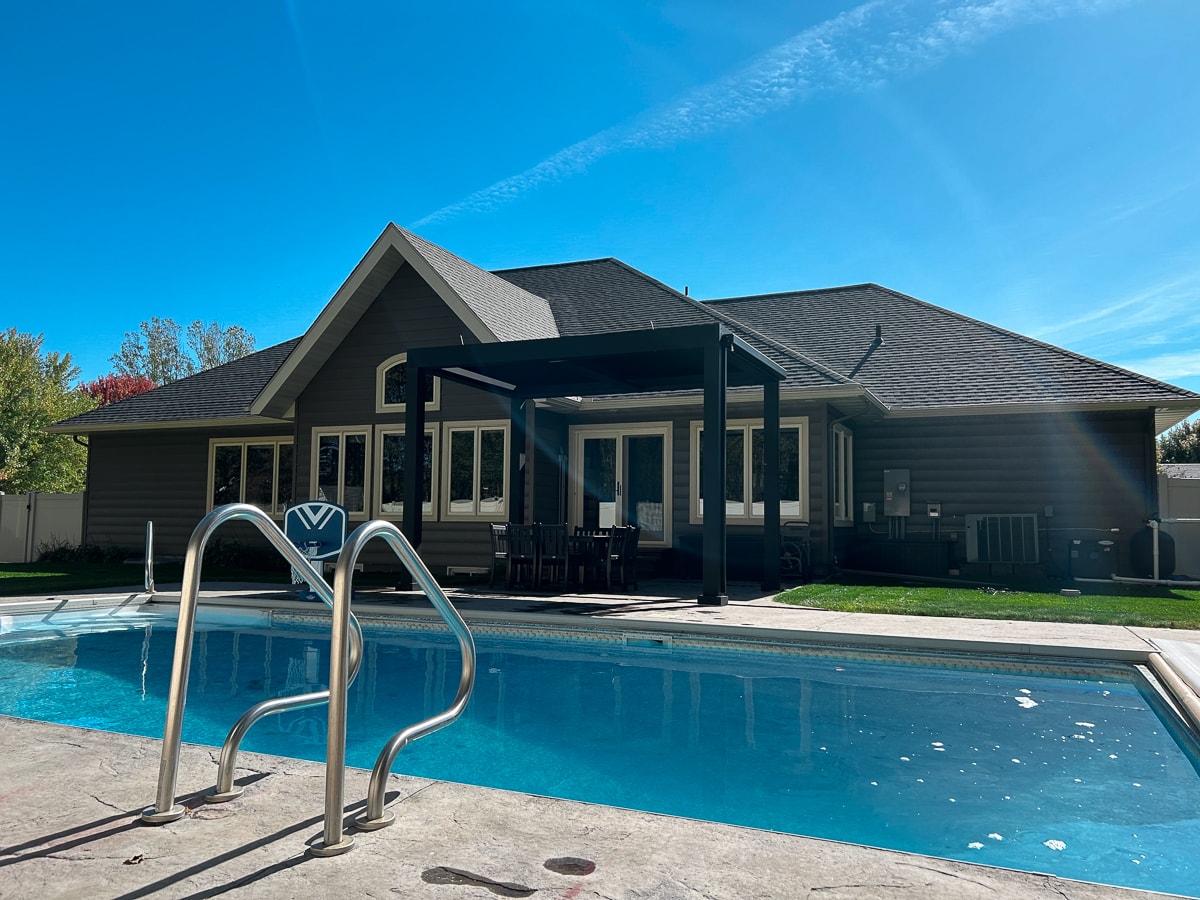 Black poolside pergola overlooking the backyard and pool area.