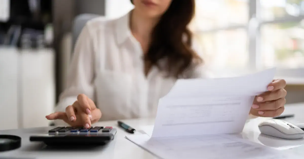 Woman organizing tax records and estimated payments using safe harbor rules for estimated taxes.