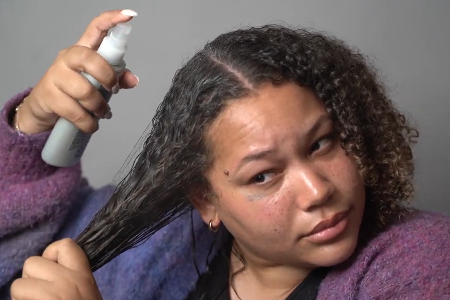 woman applying the Kenra Platinum Blow Dry Spray on her wet hair