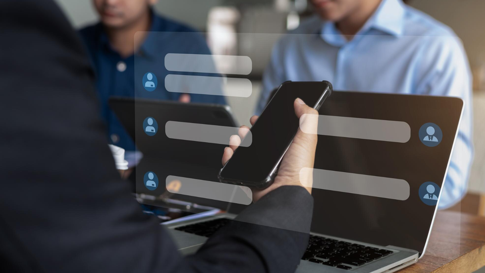 How Teams Chat and Slack Integration Enables Cross-Platform Messaging 2 Person holding a smartphone in front of a laptop with chat bubbles overlaid, representing cross-platform chat services.