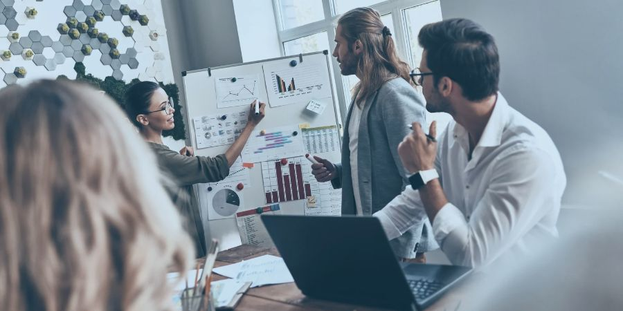 4 employees in an office looking at graphs on a board