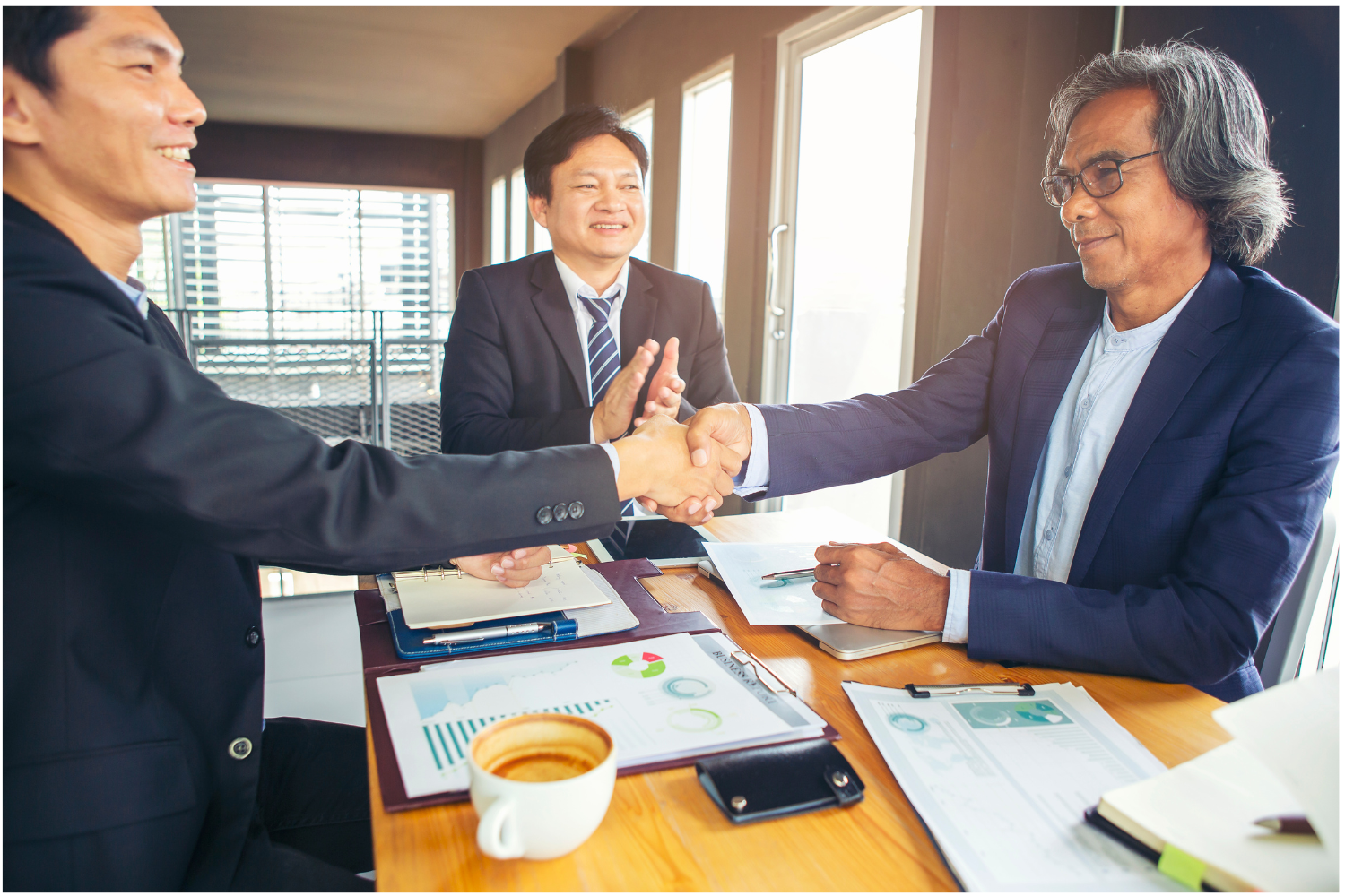 Business people shaking hands at a table.