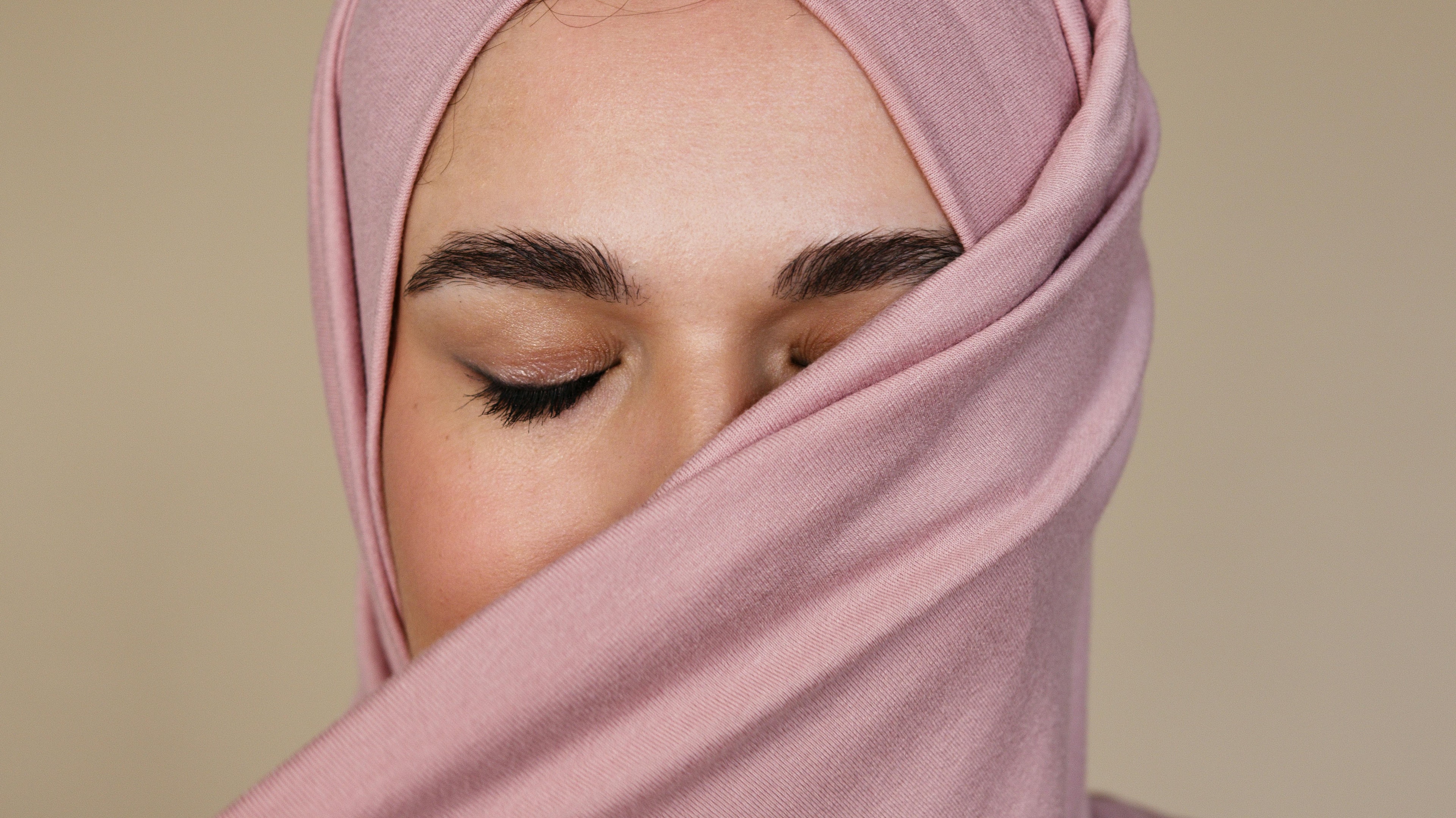 Closeup of a hijabi closing her eyes with a pink hijab hiding half her face