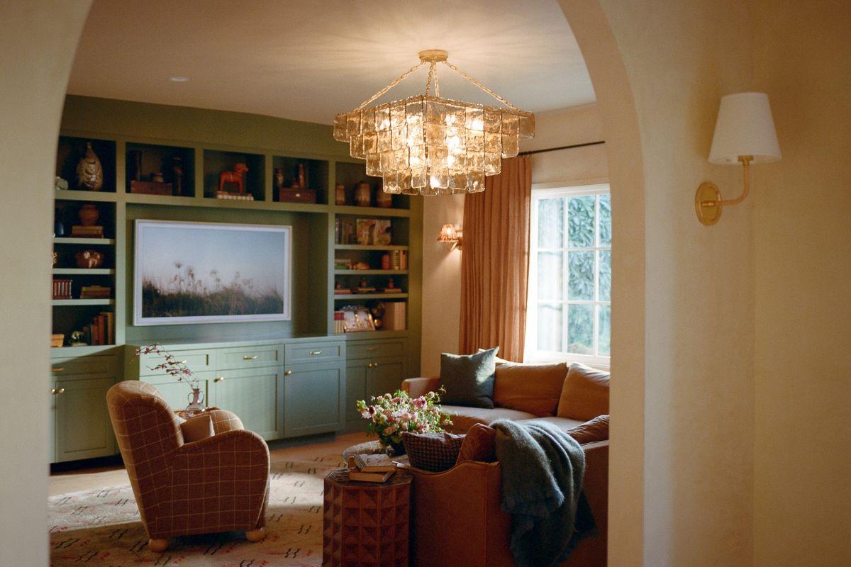 Cozy living room with a statement light fixture hanging above a table, warm wood floor, and a generally inviting layout that shows proper placement when putting lighting into a space