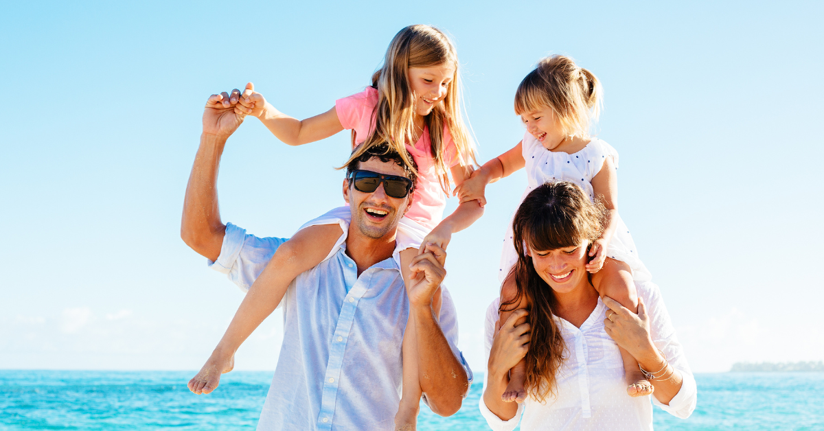 Happy family with two young children on shoulders enjoying a sunny day at Point Pleasant Beach, New Jersey — book direct and save up to 25% on Jersey Shore vacation rentals