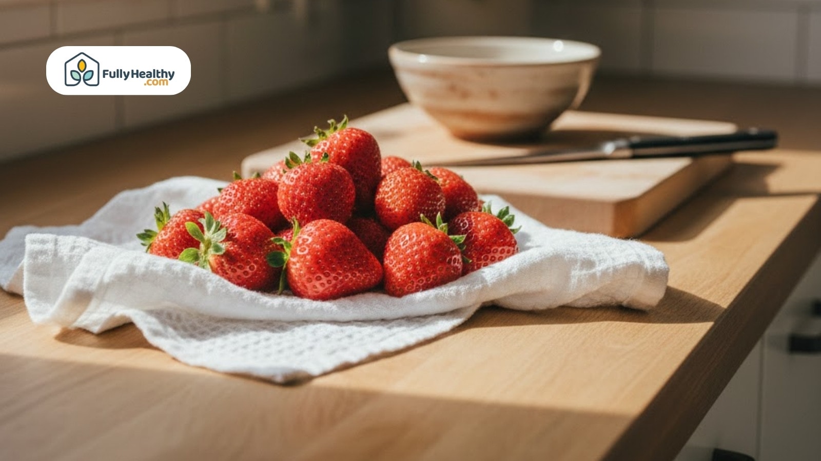 Fresh strawberries resting on a towel atop a wooden kitchen counter