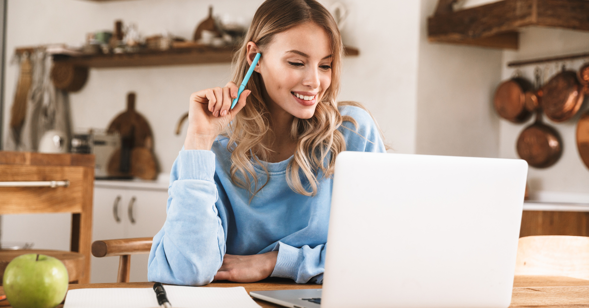 A woman reviewing Form 1040 NR on her laptop while organizing her OnlyFans income records.