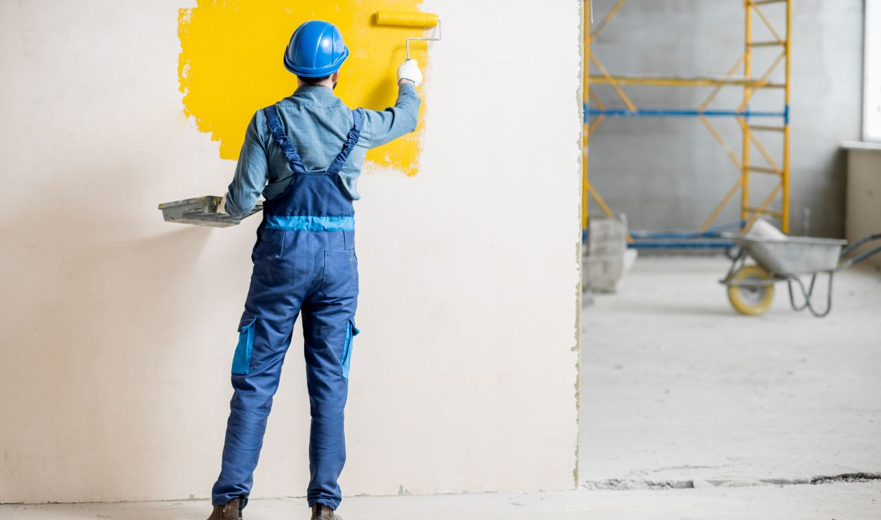 A person applying a skim coat on a ceiling using a trowel, following the how to skim coat a ceiling transforming your ceiling with ease guide.
