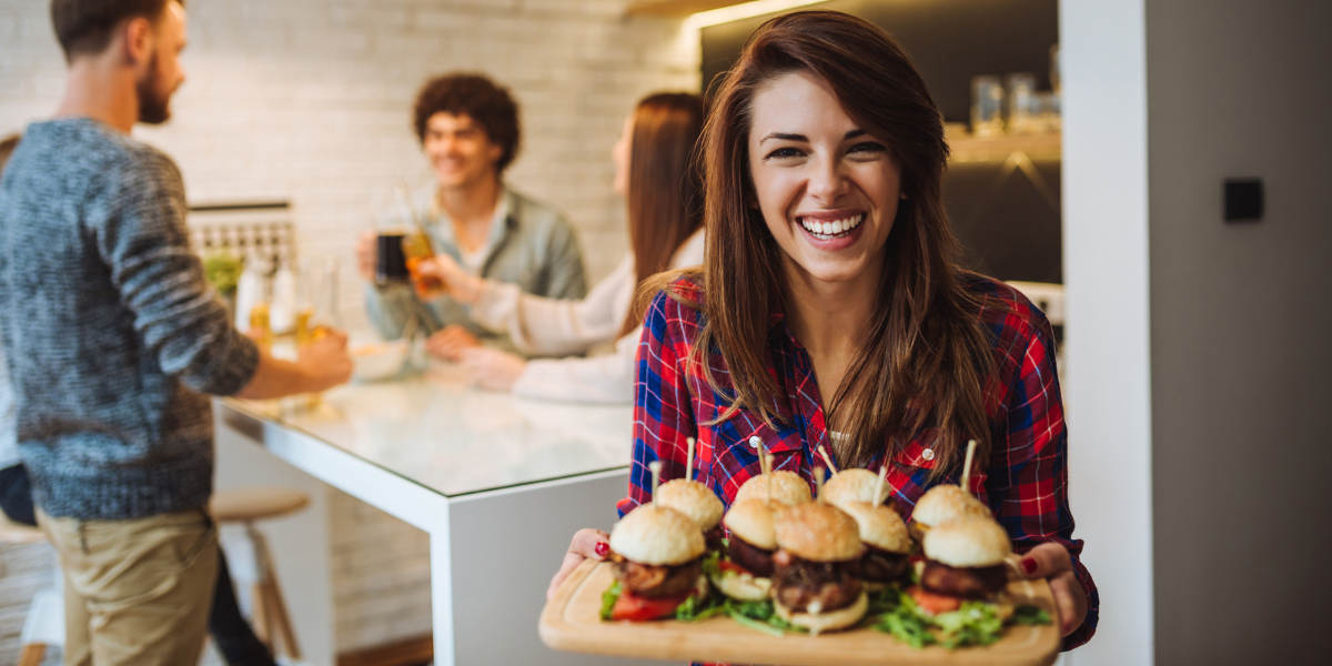 A diet break helps weight loss efforts. Woman smiling while holding a tray of sliders. 