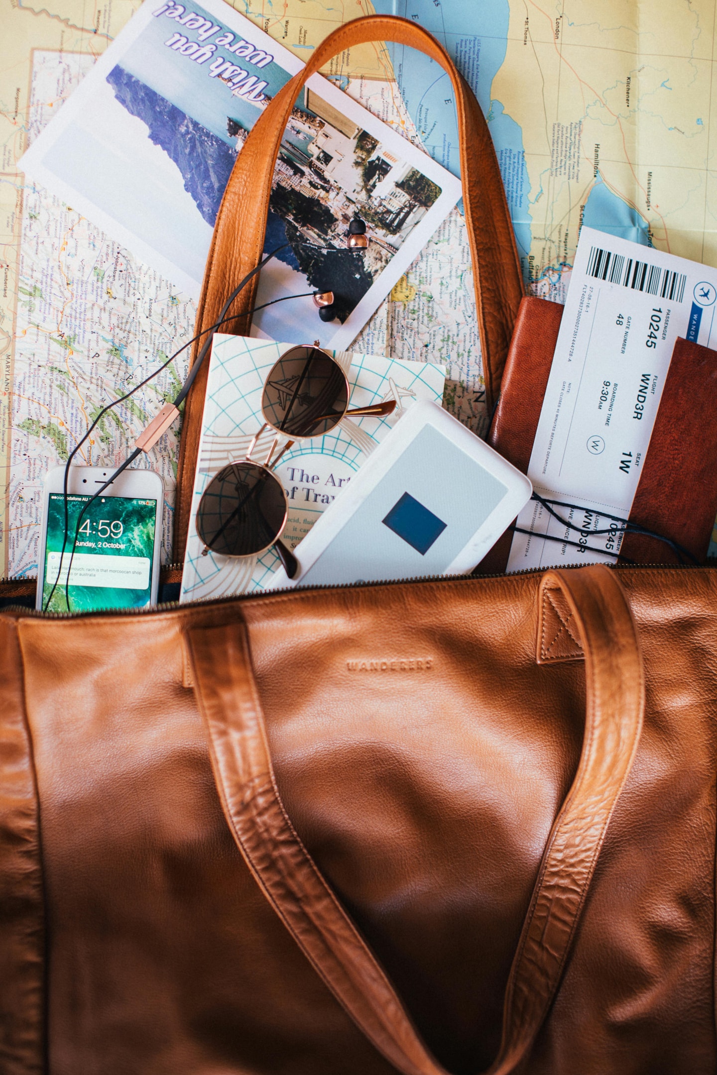 Bag with travel essentials coming out of it on top of a map