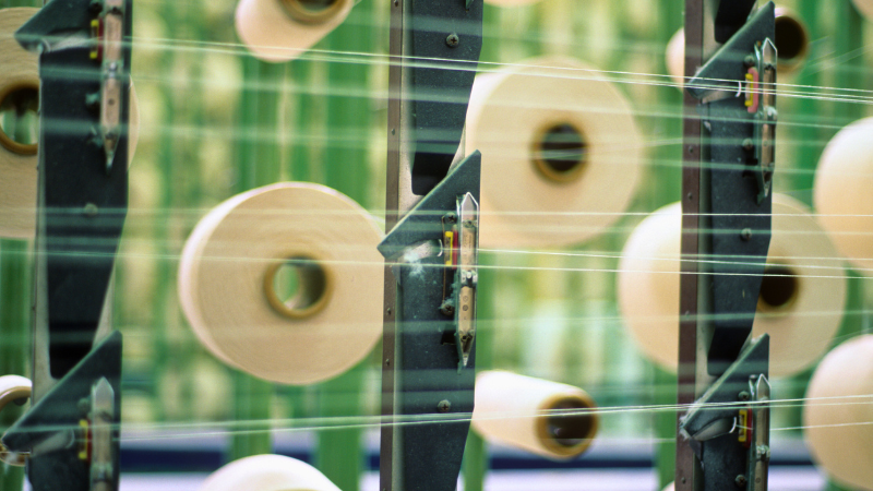 A textile machine with spools of thread in motion, creating a blurred effect.