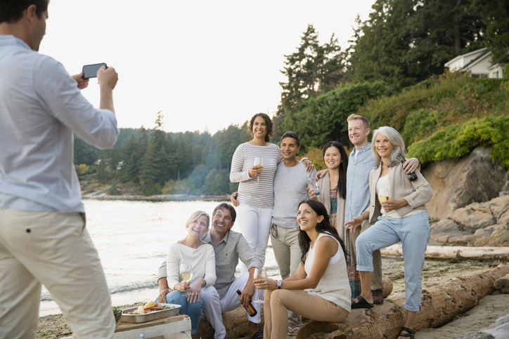 Group of happy, mature adults having their photo taken on the shore of a lake.